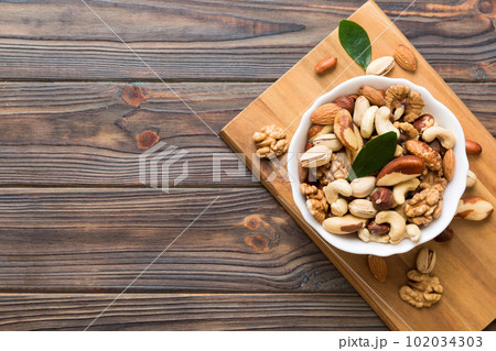 mixed nuts in bowl. Mix of various nuts on colored background. pistachios, cashews, walnuts, hazelnuts, peanuts and brazil nuts mixed nuts in bowl. Mix of various nuts on colored background. pistachios, cashews, walnuts, hazelnuts, peanuts and brazil nuts 102034303