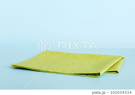 top view with green kitchen napkin isolated on table background. Folded cloth for mockup with copy space, Flat lay. Minimal style top view with green kitchen napkin isolated on table background. Folded cloth for mockup with copy space, Flat lay. Minimal style 102034314