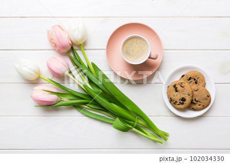 Cup of coffee mug with coffee, cookies and tulips on a colored background. Greeting spring card top view 102034330