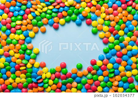 Mixed collection of colorful candy, on colored background. Flat lay, top view. frame of colorful chocolate coated candy 102034377