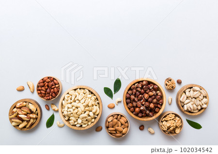 mixed nuts in wooden bowl. Mix of various nuts on colored background. pistachios, cashews, walnuts, hazelnuts, peanuts and brazil nuts 102034542