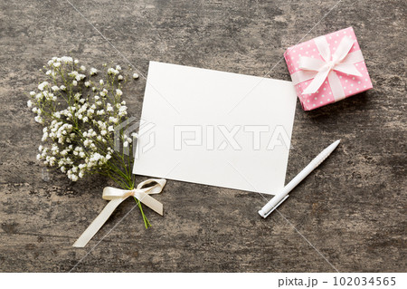 Wedding mockup with white paper list and flowers gypsophila on colored table top view flat lay. Blank greeting cards and envelopes. Beautiful floral pattern. Flat lay style 102034565