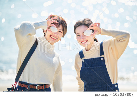 海辺で貝殻を拾う仲良しの若い女性と友達 海辺で貝殻を拾う仲良しの若い女性と友達 102037807
