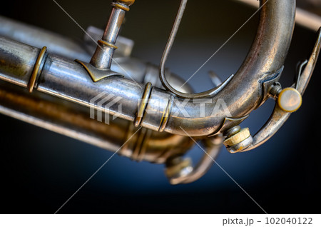 Selective focus on a water key of an aged wind instrument trumpet.  102040122
