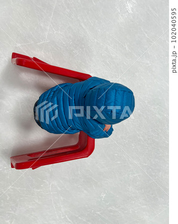 Beginner ice skater using a plastic walker for assistance. 102040595
