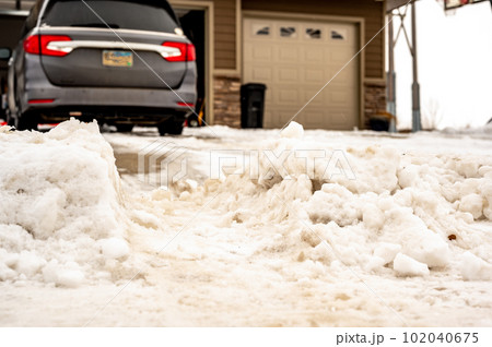 Snowbank at the end of a driveway left after city snowplows cleared a street. 102040675