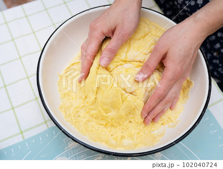 A woman kneads dough with her hands, a baker, baker's hands, dough, hands in flour, handmade baking. View from above. 102040724