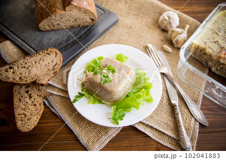 Boiled chicken meat aspic in meat gelatin broth in a plate 102041883