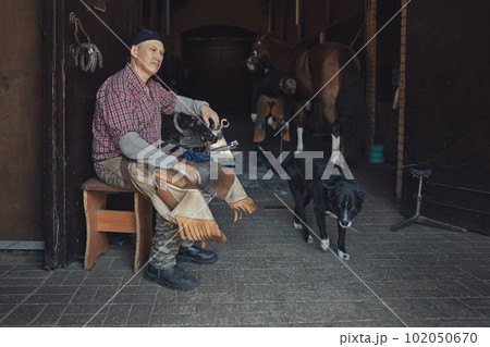 European blacksmith sits in stable next to workplace and black dog 102050670