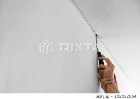 Repairman installing white stretch ceiling in room, closeup 102052964