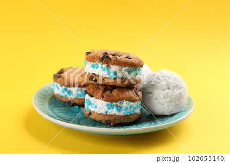 Sweet delicious ice cream cookie sandwiches on yellow background 102053140