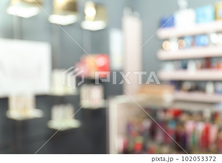 Blurred view of counter and shelves with perfume bottles in shop 102053372