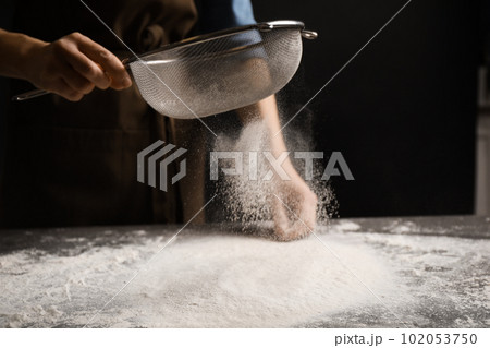 Woman sifting flour at grey table, closeup. Making pasta Woman sifting flour at grey table, closeup. Making pasta 102053750