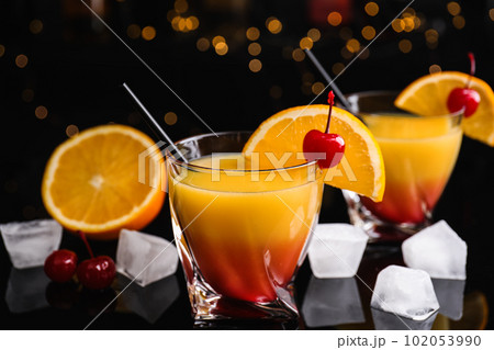 Fresh alcoholic Tequila Sunrise cocktail on black table Fresh alcoholic Tequila Sunrise cocktail on black table 102053990
