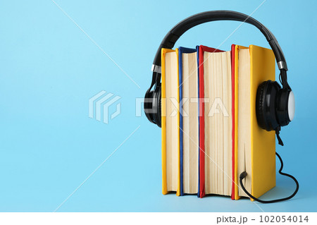Books and modern headphones on light blue background. Space for text Books and modern headphones on light blue background. Space for text 102054014