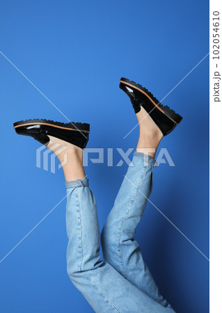 Woman wearing stylish shoes on blue background, closeup Woman wearing stylish shoes on blue background, closeup 102054610