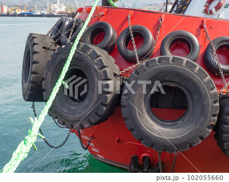 Protection of the side of the ship with car tires. Moored ship. Portholes in the hold. Ship at the pier. Equipment in the port. Protection of the side of the ship with car tires. Moored ship. Portholes in the hold. Ship at the pier. Equipment in the port. 102055660