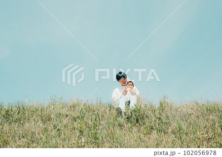 土手で座るパパと子供のファミリー写真 土手で座るパパと子供のファミリー写真 102056978
