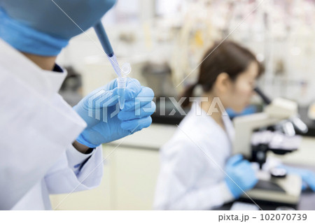 マイクロピペットを使う研究員手元 研究 開発 実験イメージ  マイクロピペットを使う研究員手元 研究 開発 実験イメージ  102070739