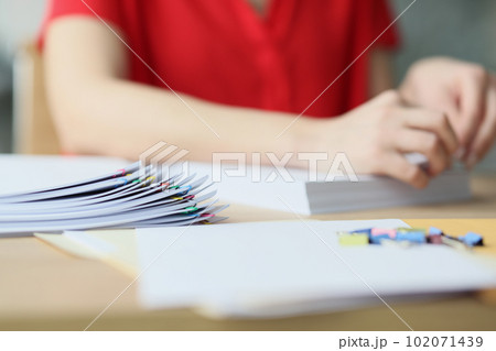 Secretary in red blouse fastens papers with pins in office 102071439