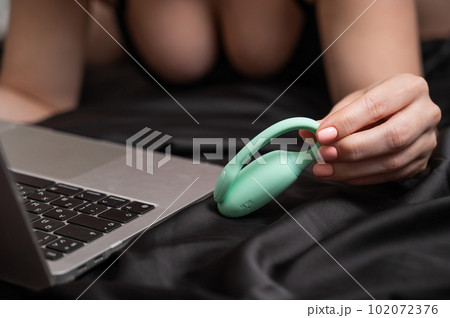 A woman lies on a bed and synchronizes the kegel machine with a laptop. A woman lies on a bed and synchronizes the kegel machine with a laptop. 102072376