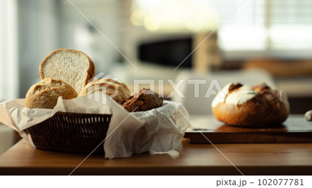 Homemade various fresh bread in a wicker basket on wooden table. Healthy eating and traditional bakery and pastry concept 102077781