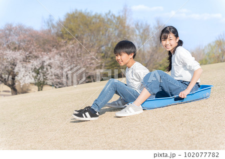 芝すべりをする仲良しの男女 102077782