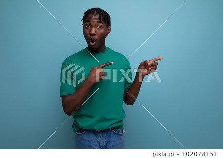 dark-skinned young man in a tank top pointing with a finger for the presence of an offer on an dark-skinned young man in a tank top pointing with a finger for the presence of an offer on an 102078151