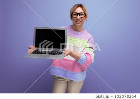 attractive blond woman freelancer with a laptop in her hands shows a screen mockup on a purple attractive blond woman freelancer with a laptop in her hands shows a screen mockup on a purple 102078254