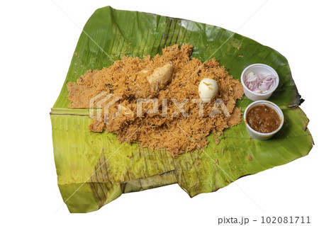 Hot chicken biryani with egg, raita and onion in banana leaf. A popular spicy non-vegetarian dish of India. top view 102081711