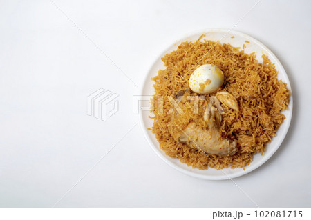 Top view of delicious spicy chicken biryani with egg on white plate, Ramadan festive food. Top view of delicious spicy chicken biryani with egg on white plate, Ramadan festive food. 102081715