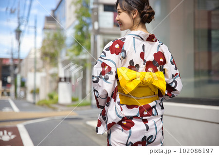 浴衣姿で街を歩く若い女性の後ろ姿 102086197