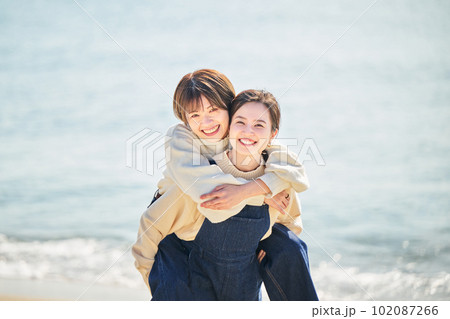 海辺で友達をおんぶする仲良しの若い女性と友達 海辺で友達をおんぶする仲良しの若い女性と友達 102087266