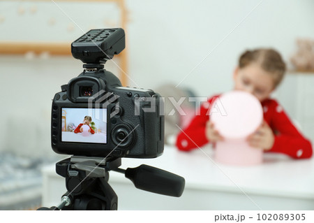 Cute little blogger with box recording video at home, focus on camera Cute little blogger with box recording video at home, focus on camera 102089305