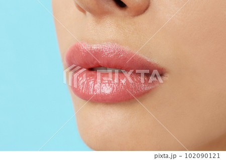 Woman with beautiful full lips on light blue background, closeup Woman with beautiful full lips on light blue background, closeup 102090121