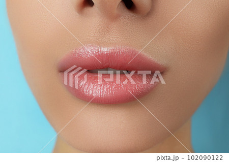 Woman with beautiful full lips on light blue background, closeup Woman with beautiful full lips on light blue background, closeup 102090122