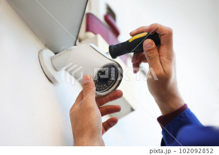 Technician installing CCTV camera on wall outdoors, closeup Technician installing CCTV camera on wall outdoors, closeup 102092852