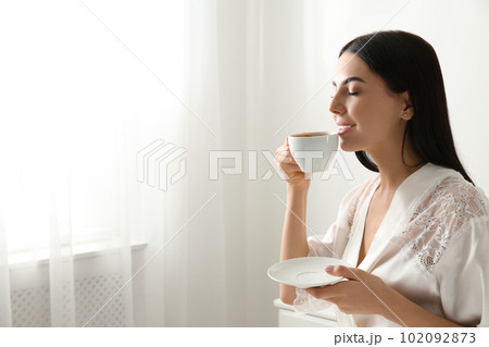 Woman with cup of coffee in bedroom. Lazy morning Woman with cup of coffee in bedroom. Lazy morning 102092873