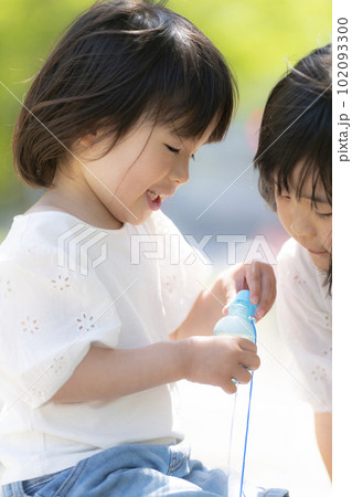 新緑の初夏の公園で遊ぶ小さな姉妹 102093300