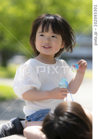 新緑の初夏の公園で遊ぶ小さな姉妹 102093301