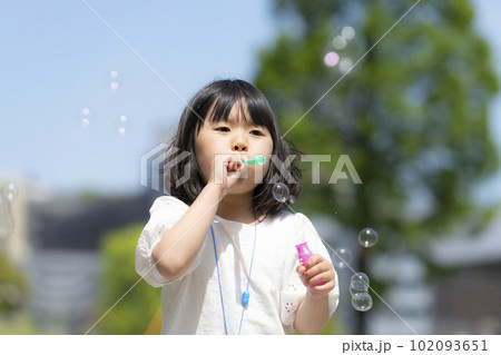 新緑の初夏の公園でシャボン玉をして遊ぶ女の子 102093651