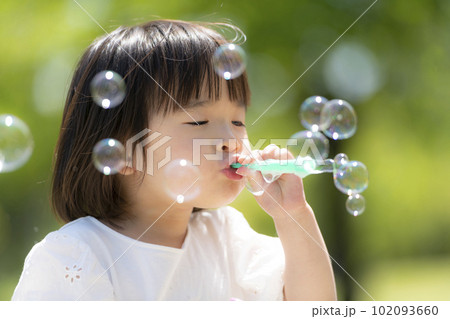新緑の初夏の公園でシャボン玉をして遊ぶ小さな女の子 新緑の初夏の公園でシャボン玉をして遊ぶ小さな女の子 102093660