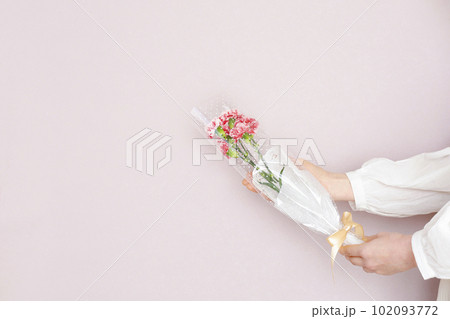 花束を持つ女性　淡いピンク背景 102093772