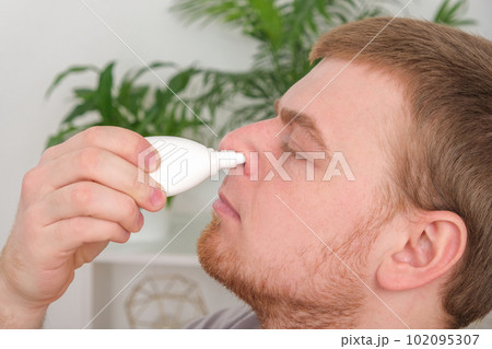 An adult male uses a nasal spray to relieve a 102095307