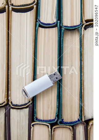 Computer usb drive on the background of a stack of old paper books. Information storage media 102096547
