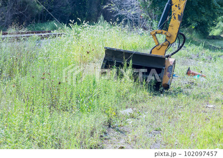 There is utility worker on side of road mowing tall grass in front his tractor using professional tractor mechanical mower 102097457