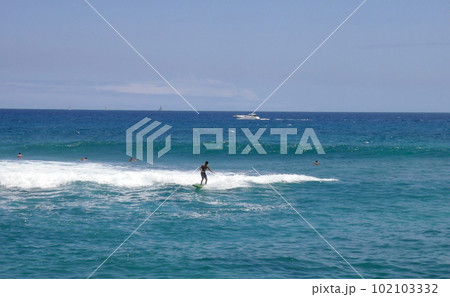 Surfer catches Wave with boat passing in backround Surfer catches Wave with boat passing in backround 102103332