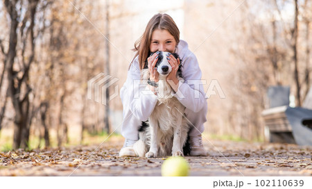 A caucasian woman hugs her dog Border Collie on a walk in the autumn park.  102110639