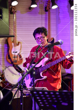 ライブハウスで演奏中のブルースバンドのベーシスト ライブハウスで演奏中のブルースバンドのベーシスト 102111354