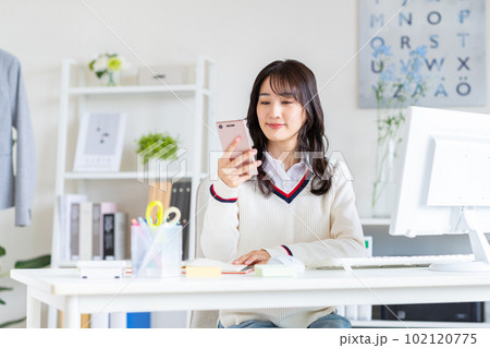 オフィスでスマホを見る若い女性 102120775